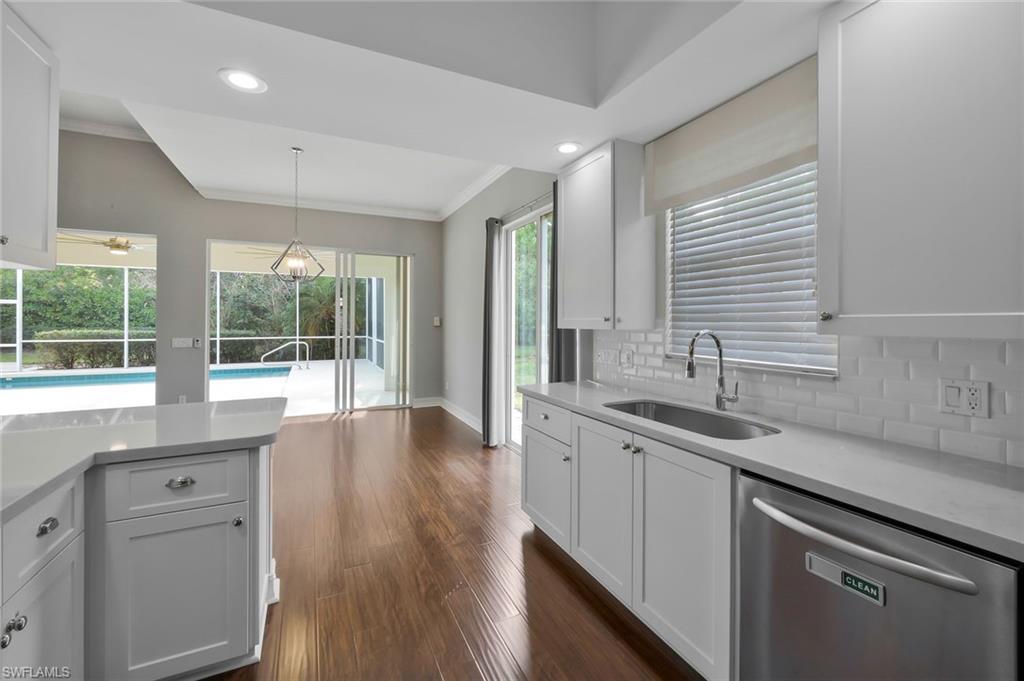 6044 Andros Way Naples, FL 34119 - Photo 6 of 46 Kitchen featuring light countertops, tasteful backsplash, dark wood-type flooring, a sink, and dishwasher
