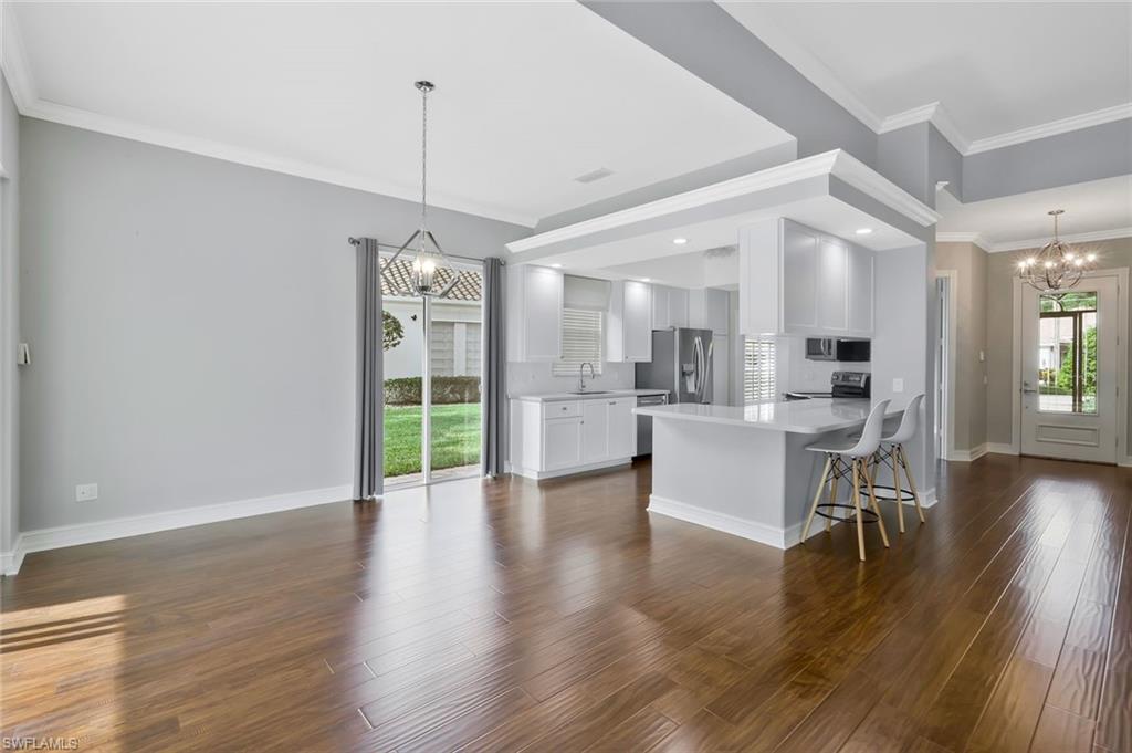 6044 Andros Way Naples, FL 34119 - Photo 8 of 46 Kitchen with dark wood-style flooring, a peninsula, appliances with stainless steel finishes, and a chandelier