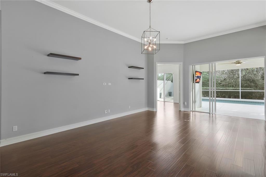 6044 Andros Way Naples, FL 34119 - Photo 9 of 46 Unfurnished room featuring baseboards, ceiling fan with notable chandelier, wood finished floors, and ornamental molding