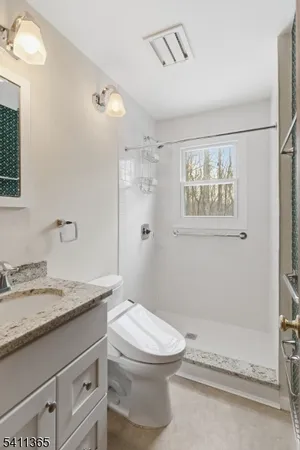 a bathroom with a granite countertop sink mirror vanity and toilet