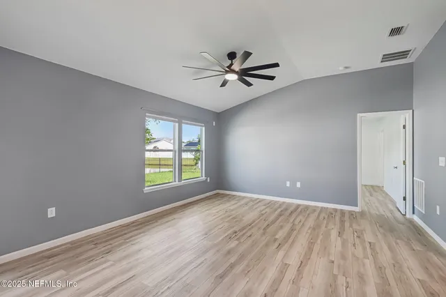 an empty room with wooden floor and windows