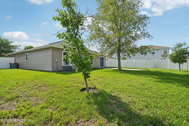 a view of a house with a yard and a large tree