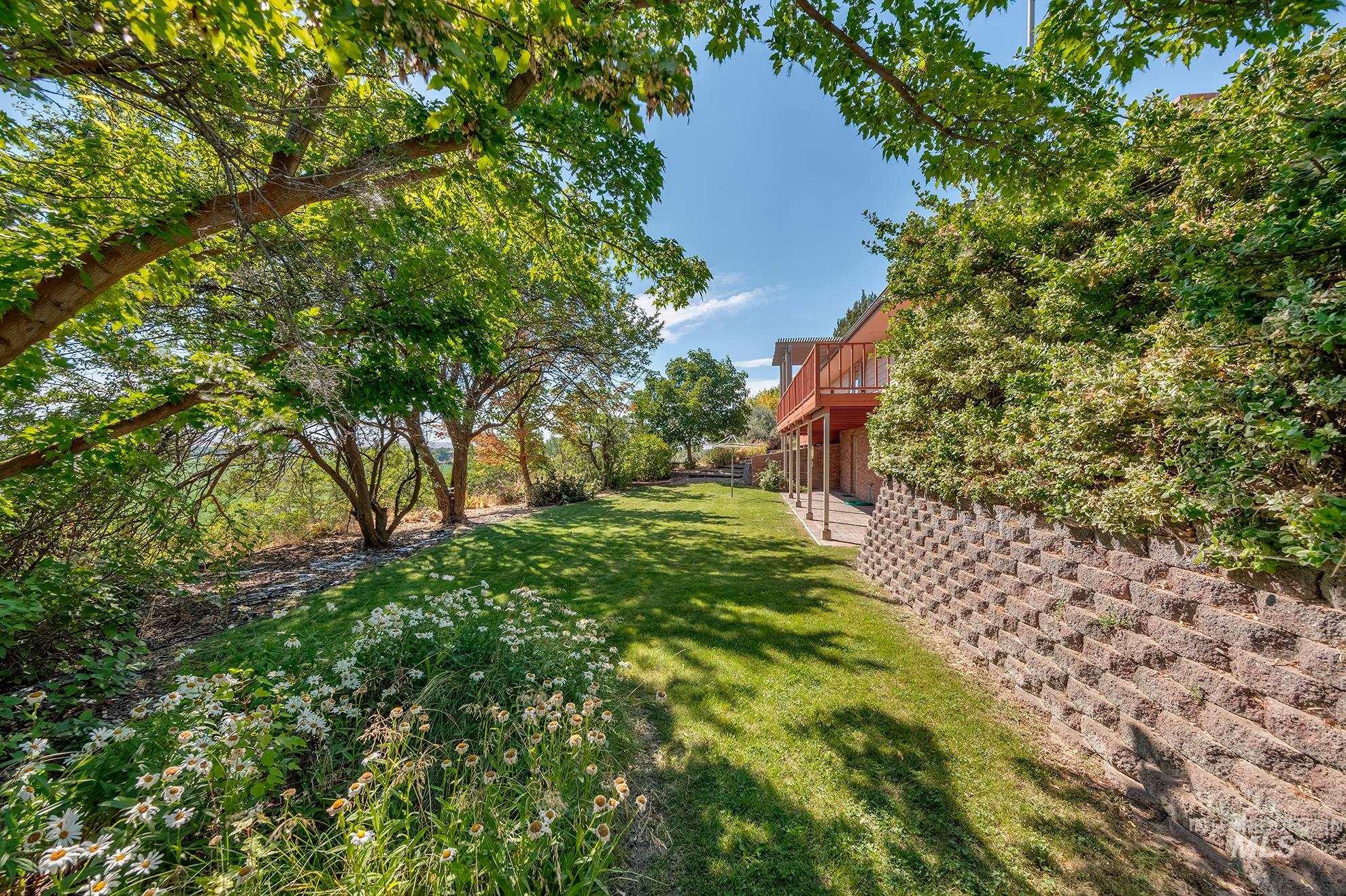 1493 Cove Road Weiser, ID 83672 - Photo 39 of 50 Expansive rear yard featuring a manicured lawn, mature trees, and a tiered retaining wall