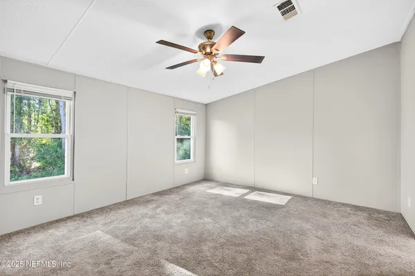 an empty room with windows and fan