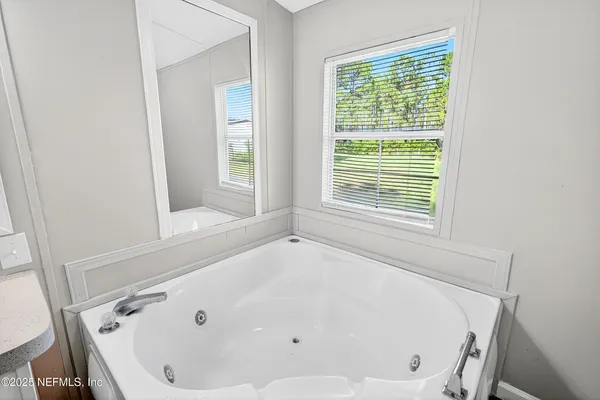a white bath tub sitting in a bathroom next to a window