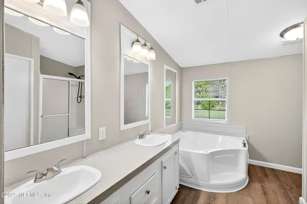 a bathroom with a double vanity sink a mirror and a bathtub