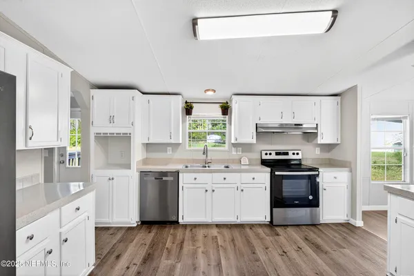 a kitchen with stainless steel appliances a stove top oven a sink a refrigerator a center island and cabinets