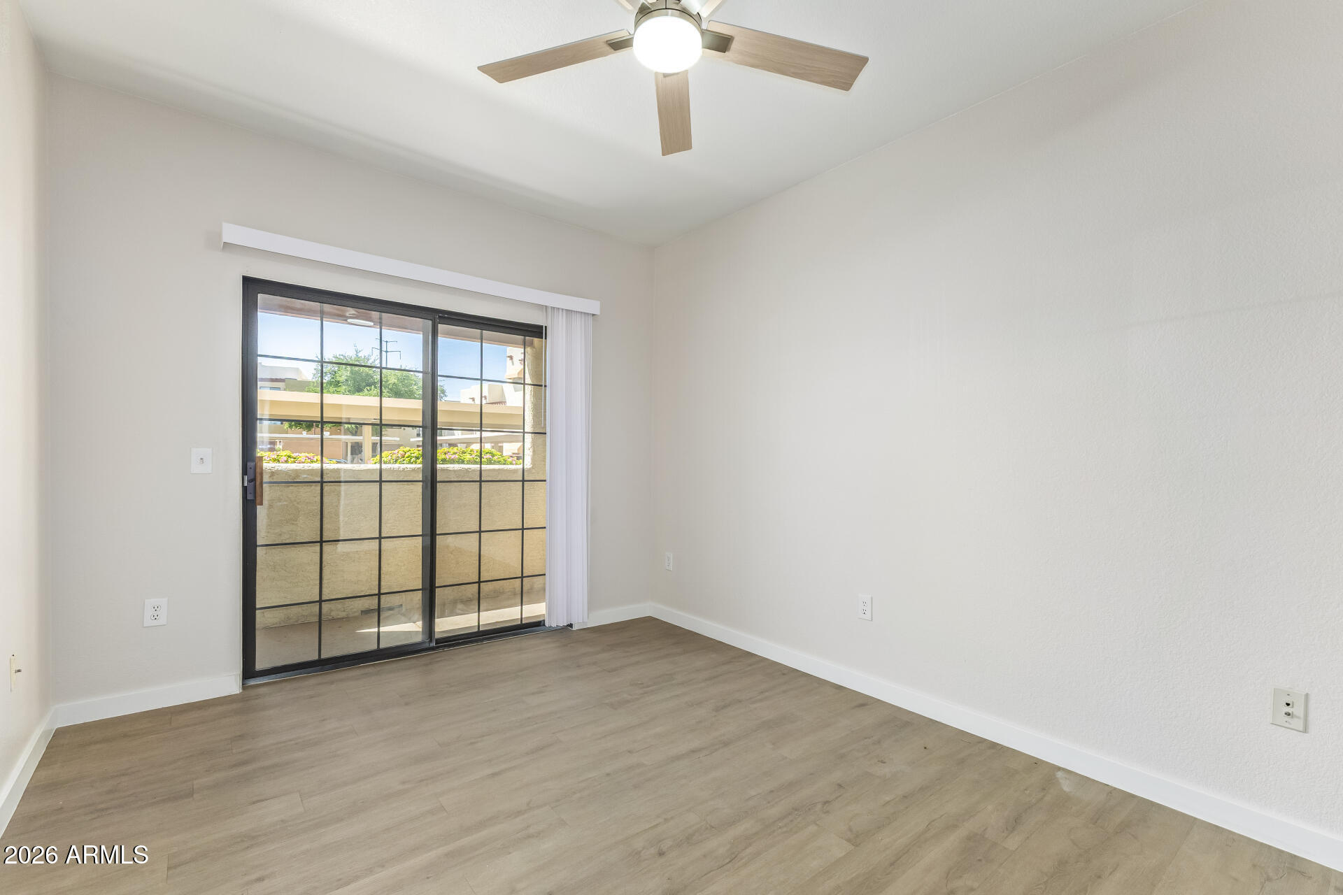 3434 East Baseline Road, Unit 109 Phoenix, AZ 85042 - Photo 13 of 40 an empty room with wooden floor chandelier fan and windows