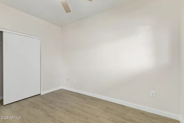 an empty room with wooden floor chandelier fan and windows