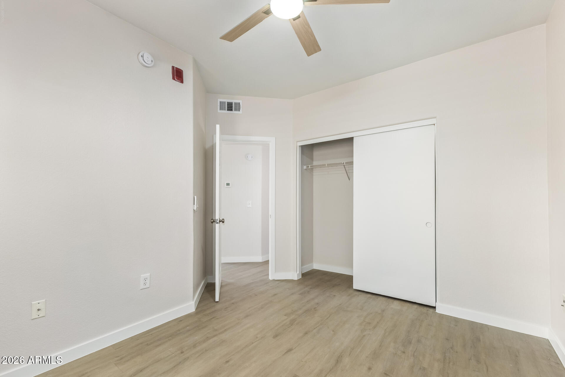 3434 East Baseline Road, Unit 109 Phoenix, AZ 85042 - Photo 23 of 40 an empty room with wooden floor chandelier fan and windows