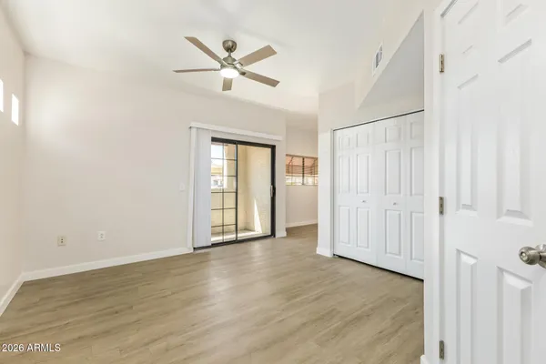 an empty room with wooden floor fan and windows