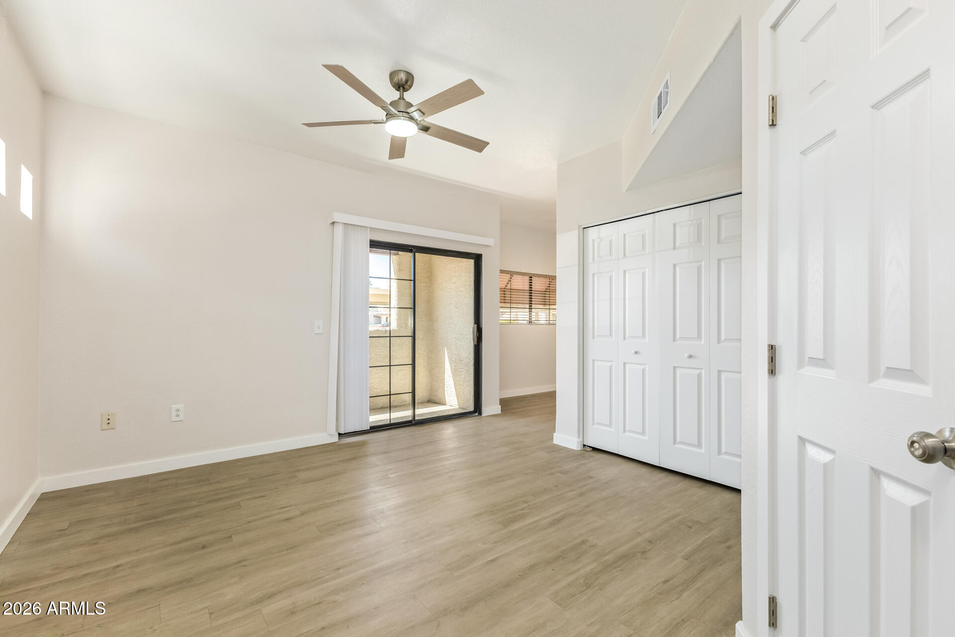 3434 East Baseline Road, Unit 109 Phoenix, AZ 85042 - Photo 5 of 40 an empty room with wooden floor fan and windows