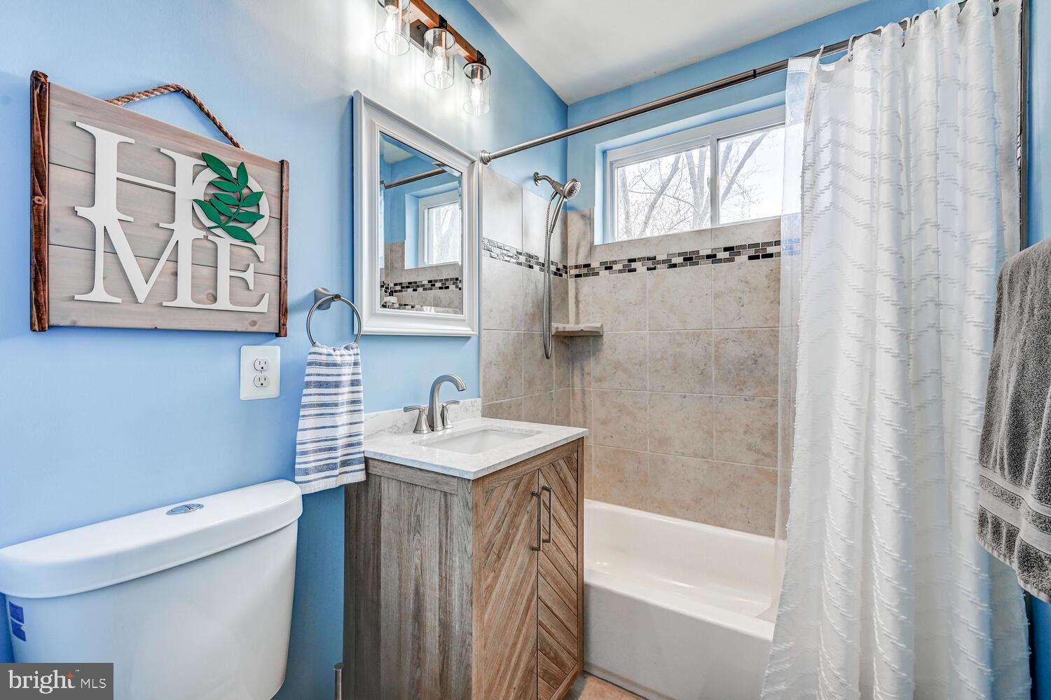 6420 Kenwood Avenue Rosedale, MD 21237 - Photo 14 of 22 a bathroom with a sink a toilet a mirror a vanity and bathtub