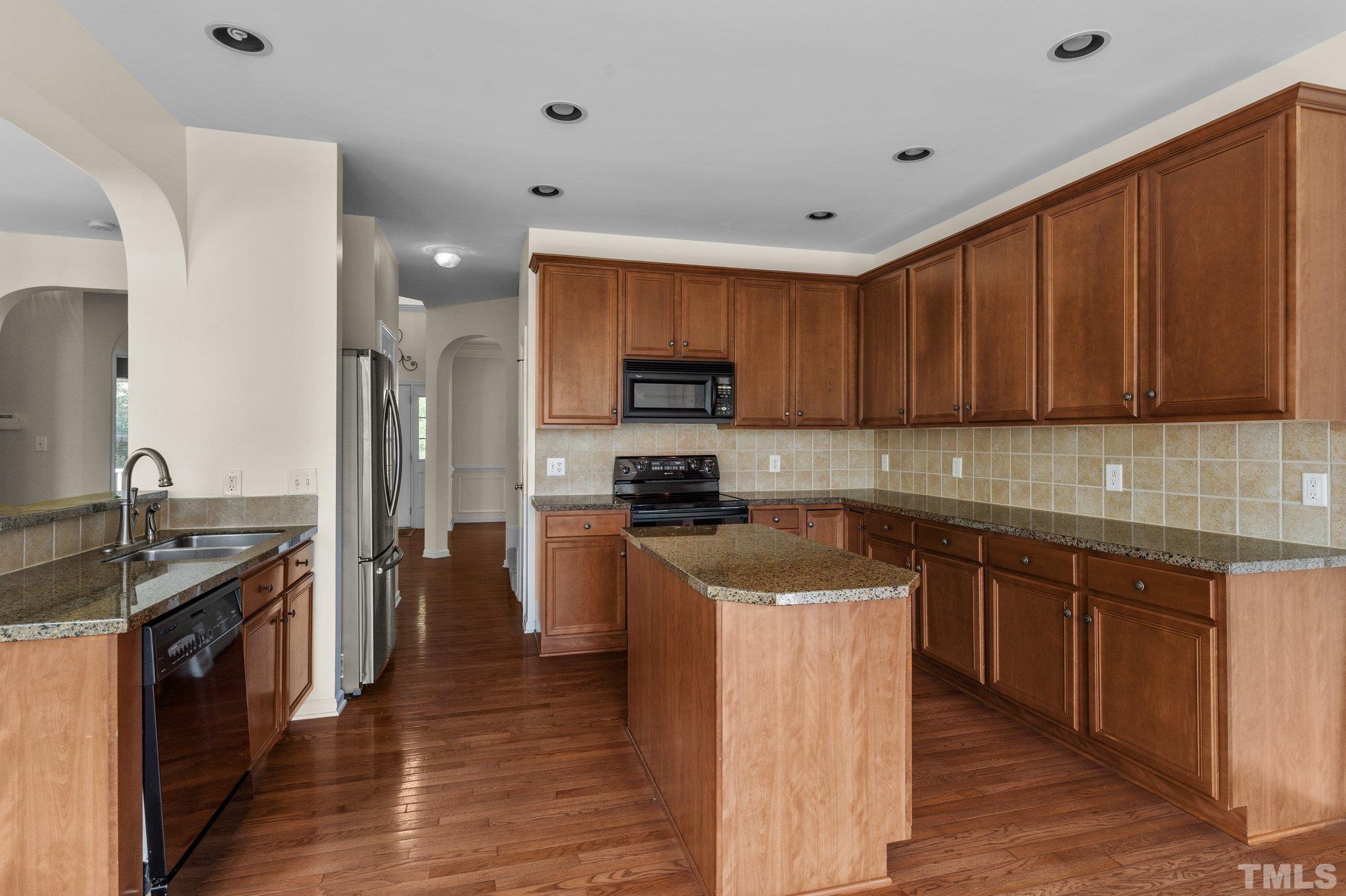 6010 Clarks Fork Drive Raleigh, NC 27616 - Photo 13 of 40 a kitchen with stainless steel appliances granite countertop wooden cabinets a stove top oven a sink and dishwasher