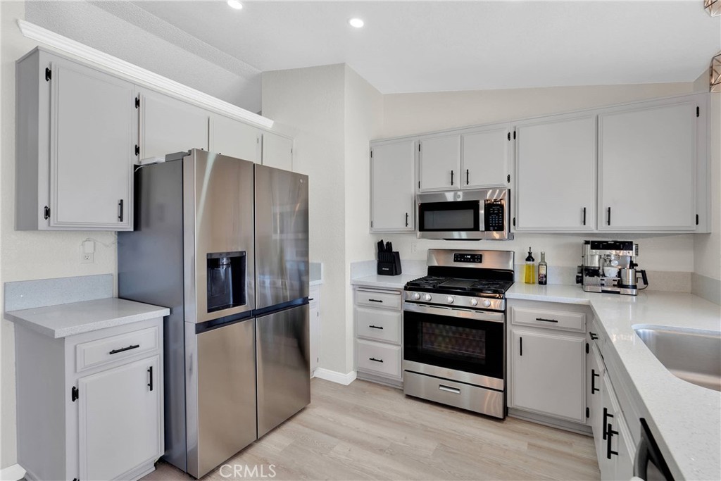 14769 Nanticoke Road Apple Valley, CA 92307 - Photo 11 of 30 a kitchen with white cabinets and stainless steel appliances
