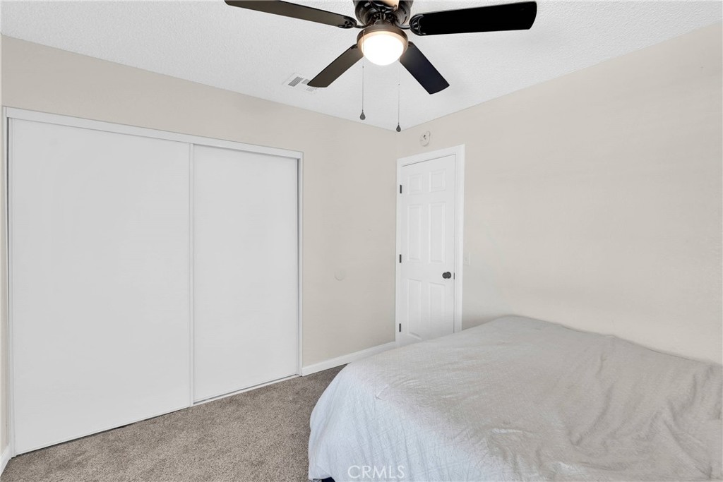 14769 Nanticoke Road Apple Valley, CA 92307 - Photo 22 of 30 a bedroom with a bed and a chandelier fan