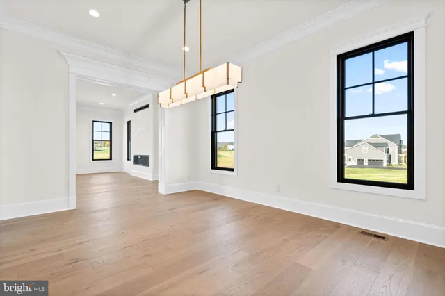 a view of an empty room with window and wooden floor