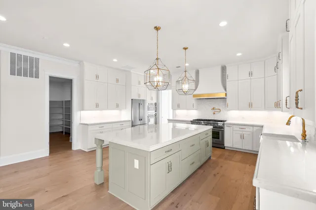 a large kitchen with kitchen island a stove a sink a center island and a refrigerator