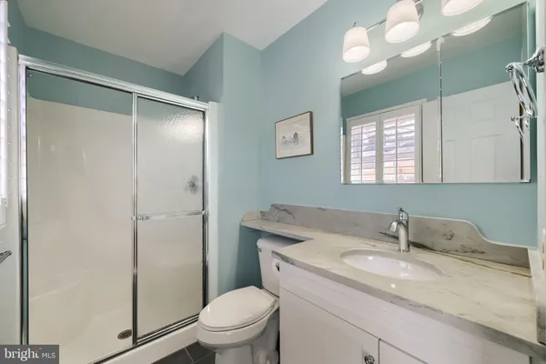 a bathroom with a granite countertop sink a toilet and a shower