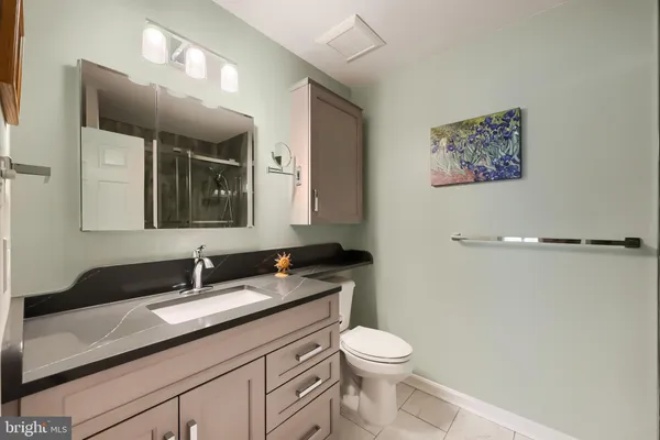 a bathroom with a granite countertop sink mirror vanity and toilet