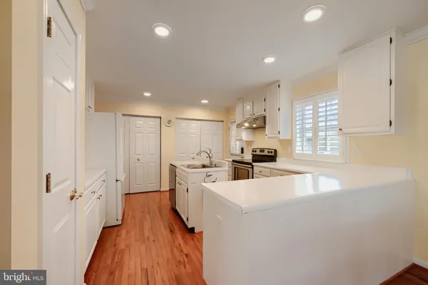 a large white kitchen with a sink a counter top space stainless steel appliances and cabinets
