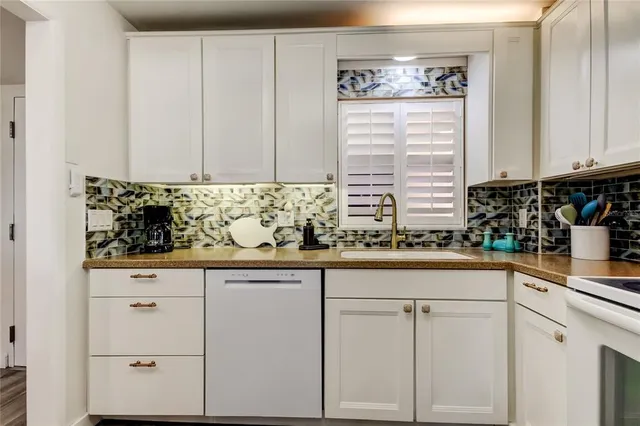 a kitchen with stainless steel appliances granite countertop white cabinets and a window