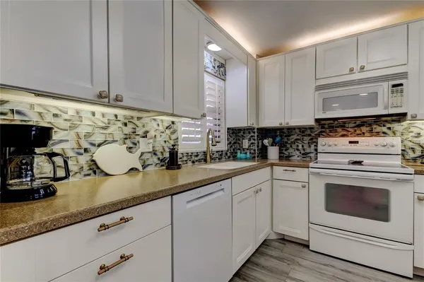 a kitchen with granite countertop white cabinets and white appliances