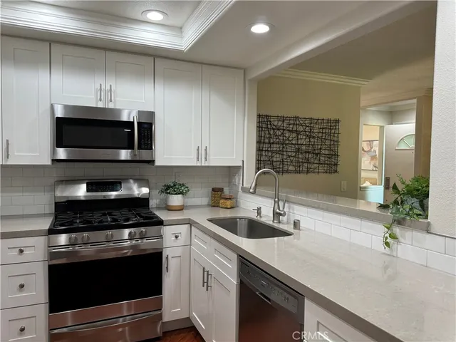 a kitchen with stainless steel appliances a stove a sink a microwave and cabinets