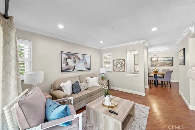a living room with furniture kitchen view and a wooden floor
