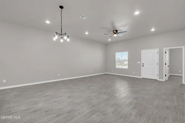 an empty room with wooden floor ceiling fan and windows