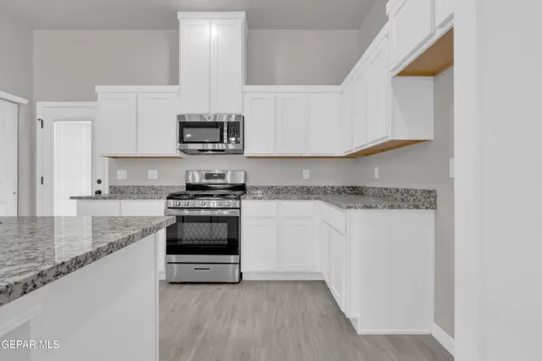 a large kitchen with kitchen island a stove a sink a center island and wooden floor