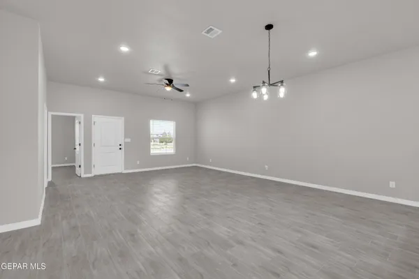 a kitchen with stainless steel appliances granite countertop a sink a stove a refrigerator and white cabinets with wooden floor