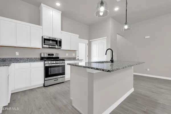 a kitchen with granite countertop a stove and a microwave