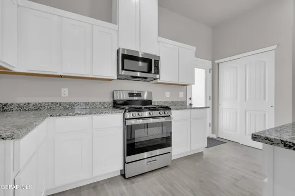 a kitchen with granite countertop white cabinets and stainless steel appliances