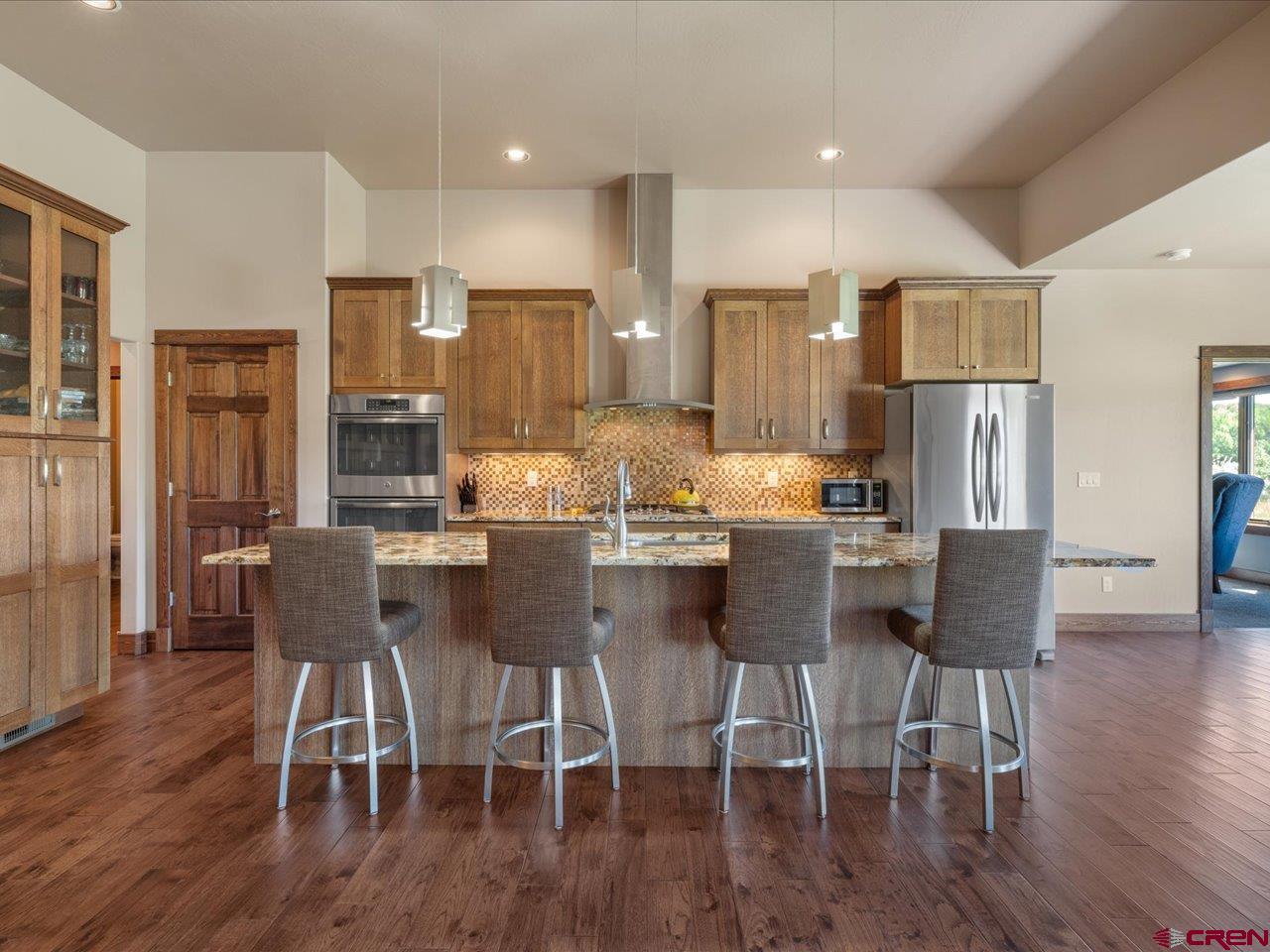 20784 6840th Road Montrose, CO 81403 - Photo 12 of 35 a kitchen with stainless steel appliances kitchen island granite countertop a refrigerator a stove a dining table and chairs with wooden floor