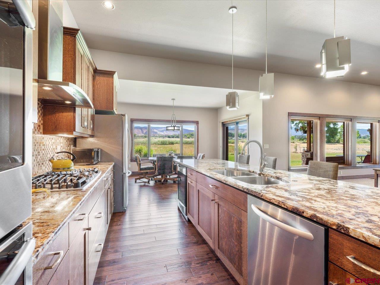20784 6840th Road Montrose, CO 81403 - Photo 13 of 35 a kitchen with stainless steel appliances kitchen island granite countertop a lot of counter space and wooden floors
