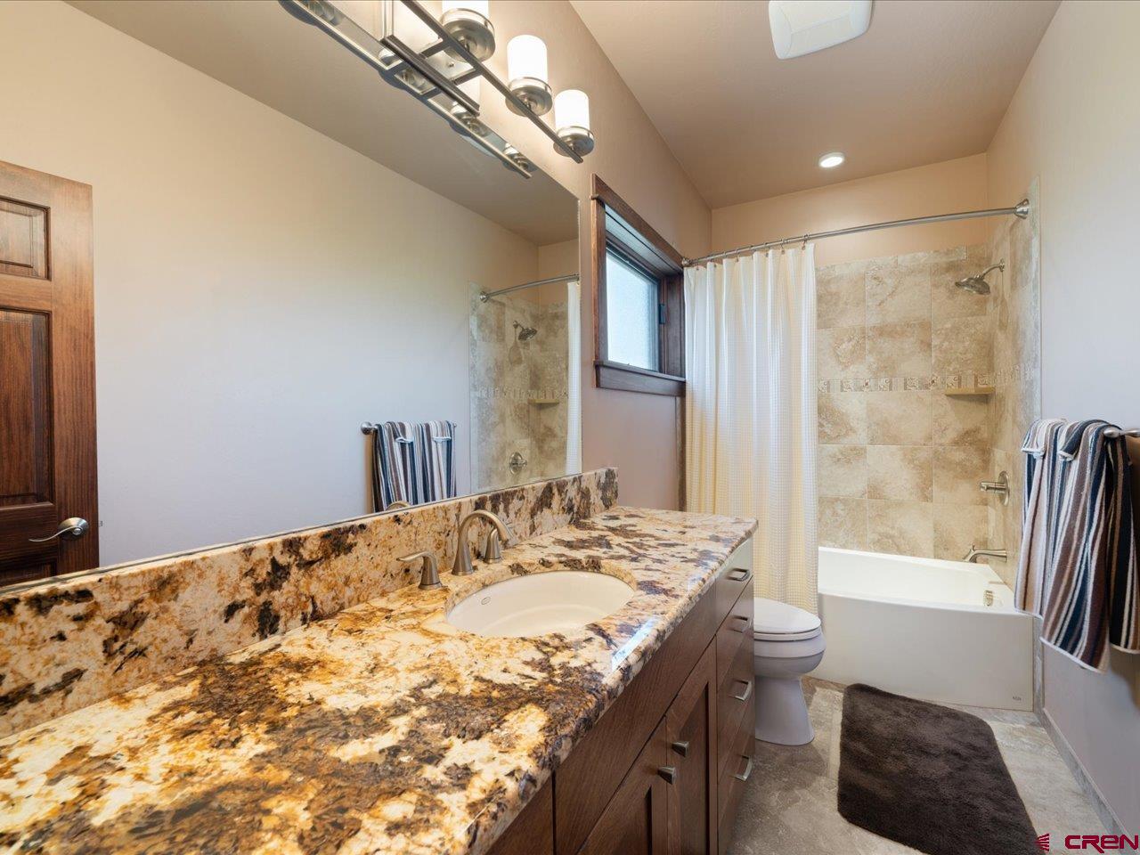 20784 6840th Road Montrose, CO 81403 - Photo 28 of 35 a bathroom with a granite countertop sink a toilet a mirror and shower
