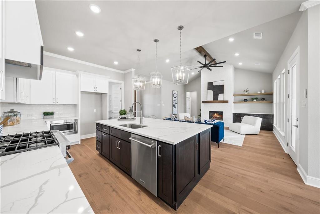 6421 Starlight Ranch Road Godley, TX 76044 - Photo 13 of 39 a large kitchen with stainless steel appliances a stove a sink dishwasher and a dining table with wooden floor