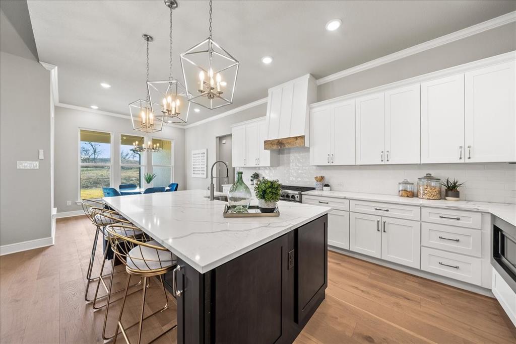 6421 Starlight Ranch Road Godley, TX 76044 - Photo 15 of 39 a kitchen with a stove a sink a center island and cabinets