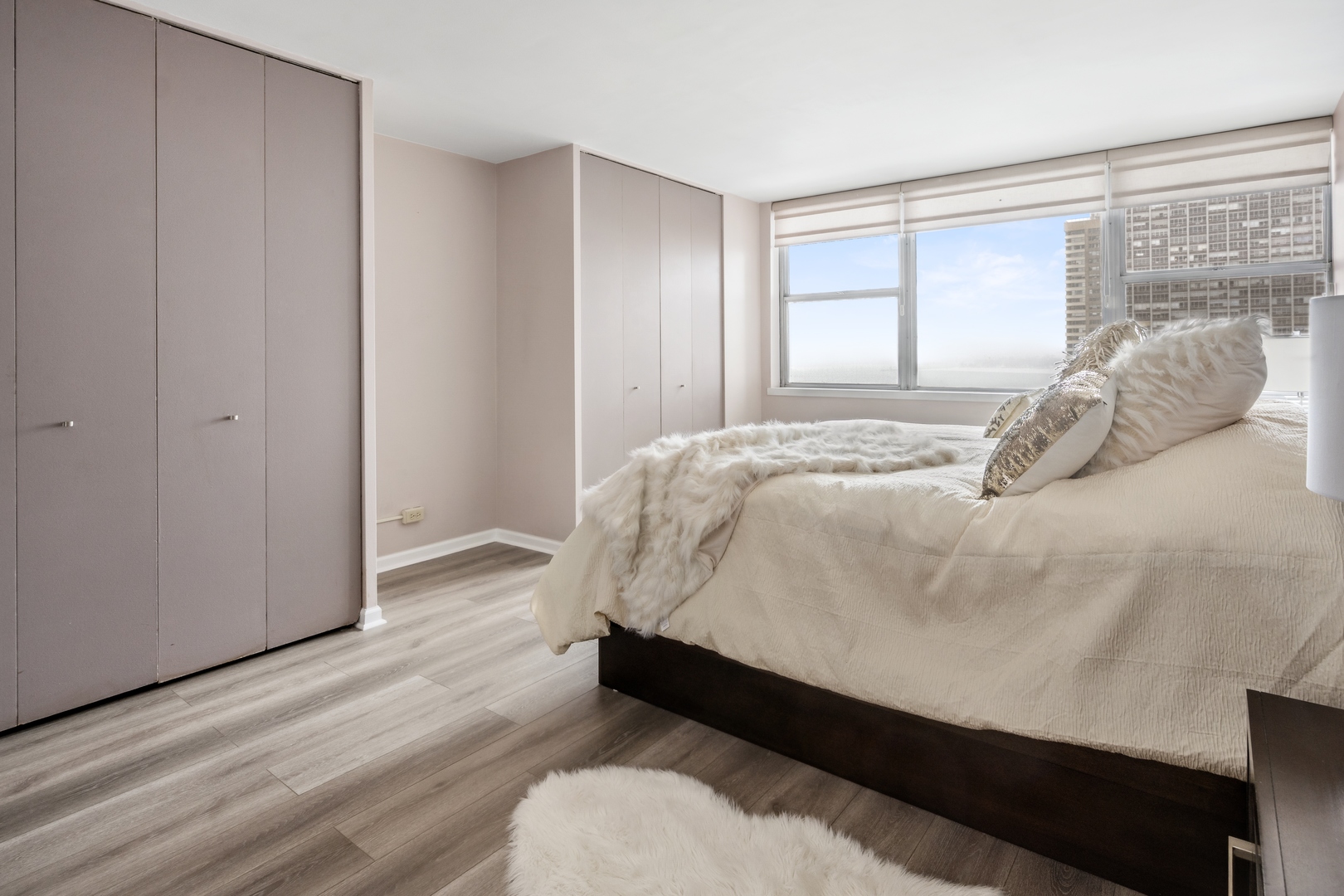 6301 North Sheridan Road, Unit 8E Chicago, IL 60660 - Photo 10 of 19 a bed sitting in a bedroom next to a window and a wooden floor