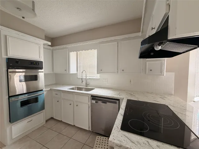 a kitchen with a sink dishwasher and a stove top oven with wooden floor