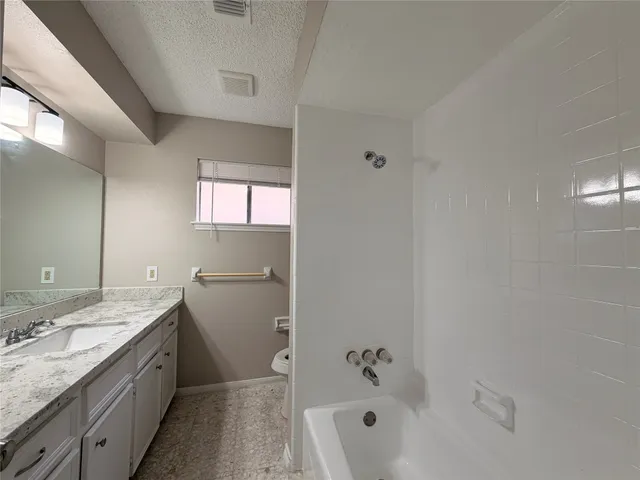 a bathroom with a granite countertop sink a toilet and bathtub