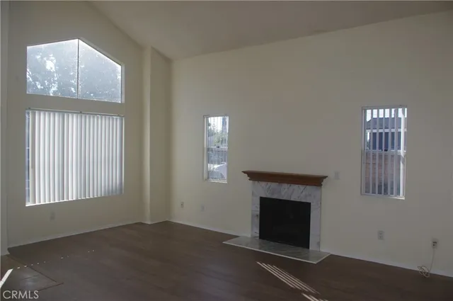 a view of an empty room with wooden floor fireplace and a window