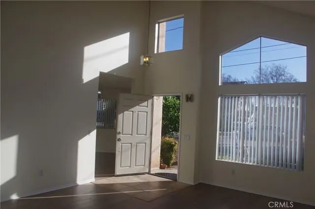 an empty room with wooden floor windows and entryway