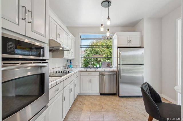 a kitchen with white cabinets and appliances