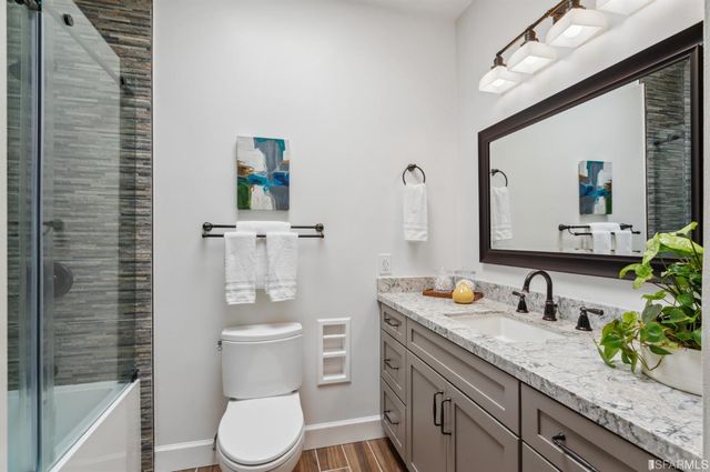 a bathroom with a granite countertop toilet sink and mirror