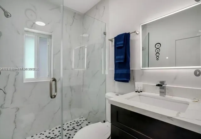 a bathroom with a sink toilet a mirror and shower