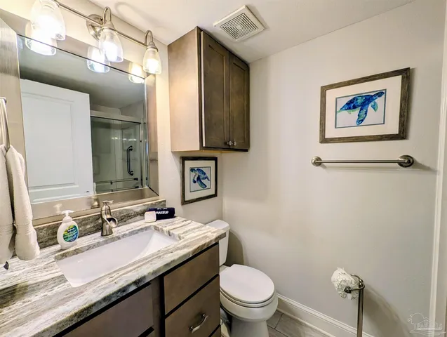 a bathroom with a granite countertop toilet sink and mirror