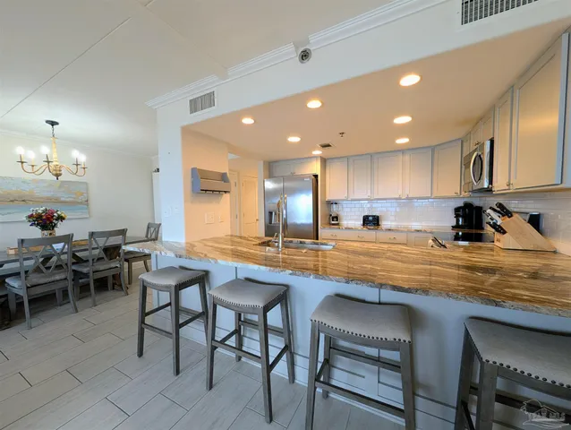a kitchen with stainless steel appliances granite countertop table chairs sink and cabinets
