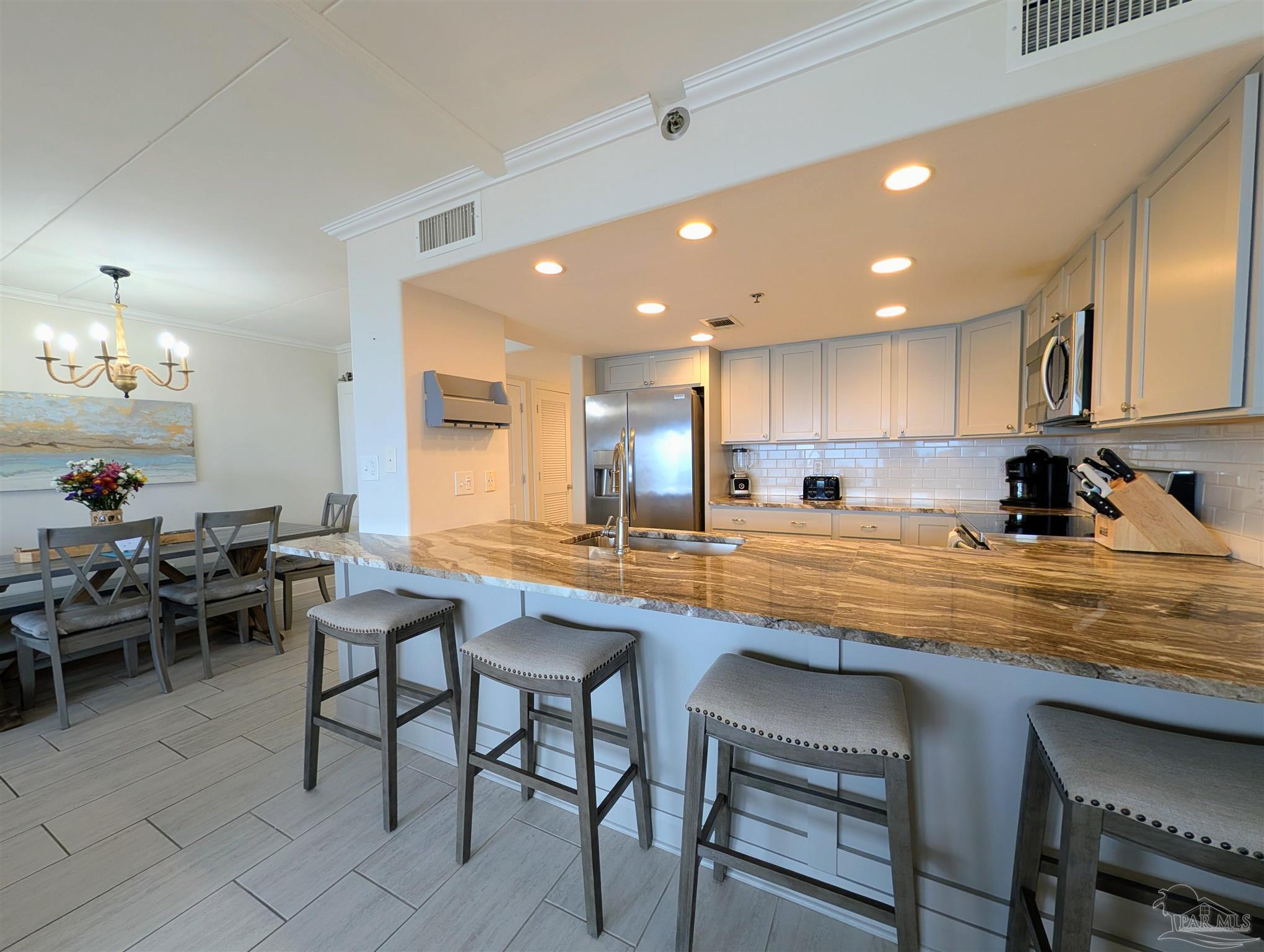 14623 Perdido Key Drive, Unit 401 Perdido Key, FL 32507 - Photo 8 of 40 a kitchen with stainless steel appliances granite countertop table chairs sink and cabinets